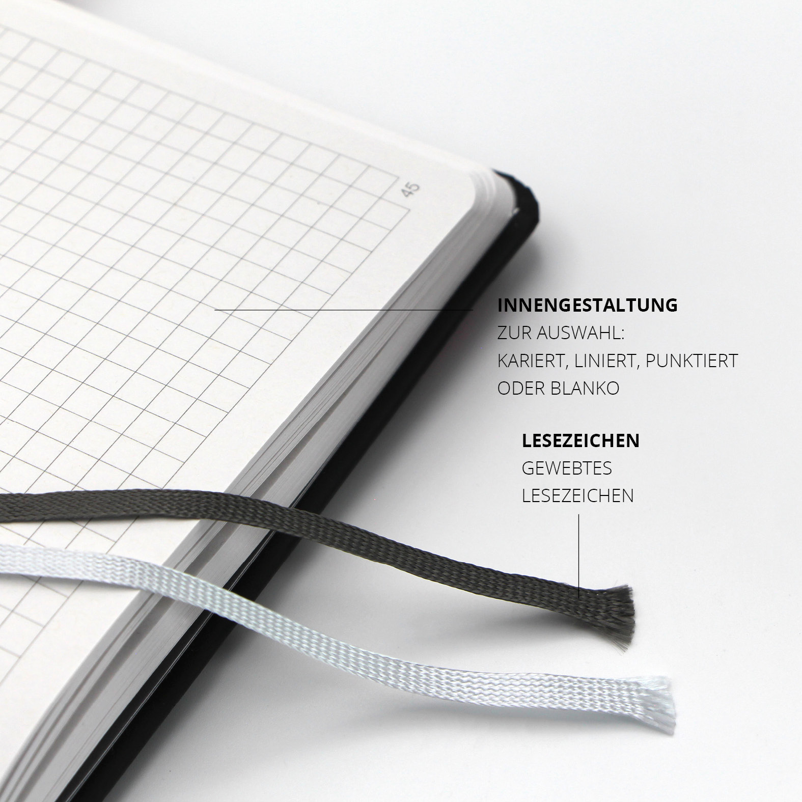 Zwei gewebte Lesezeichen in Schwarz und Weiß auf karierter Innenseite des Lanybook® Nature. Seitenzahlen sichtbar, wahlweise kariert, liniert, punktiert oder blanko.