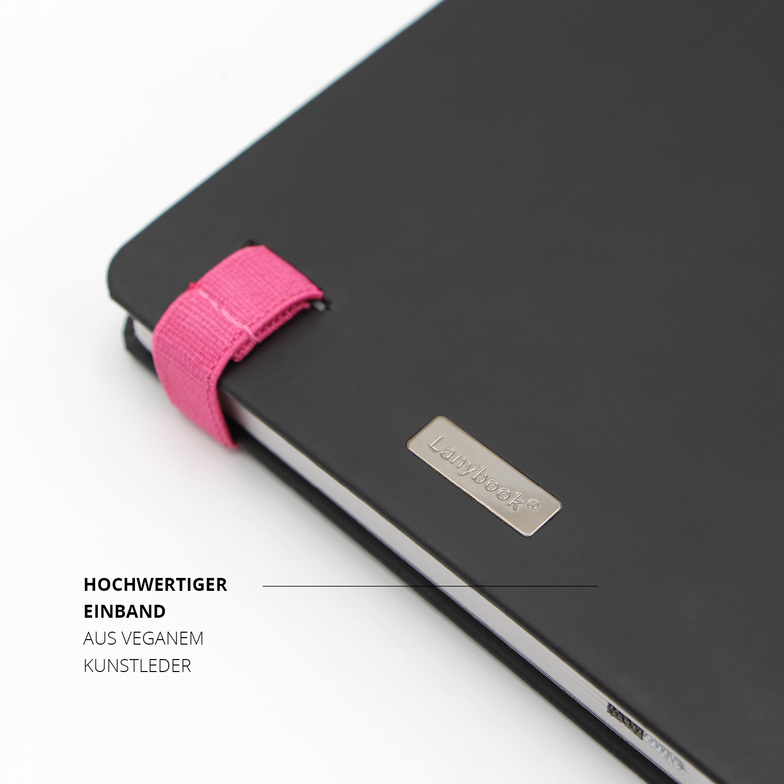 Detailansicht des Lanybook® Nature Notizbuchs mit pinker Stiftschlaufe und Metallplakette mit Lanybook® Logo. Schwarzer veganer Einband mit weicher Haptik.